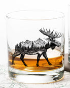 Glass with moose and mountain design filled with whiskey on a map background